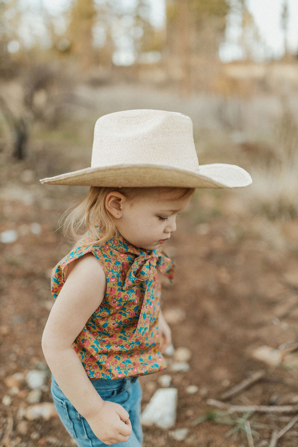 little cowgirl wearing palmleaf hat and unchained eight sleeveless lacey shirt country and western shirt for baby and kids both boys and girls areana kids crule girl shirt in wrangler jeans or cinch jeans mavericks western wear ringers western