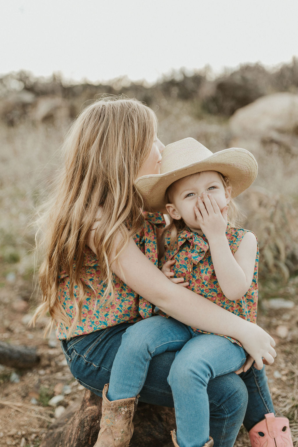 little cowgirl laughing with sister wearing unchained eight cute country kid wearing unchained eight cinch jeans mavericks western wear ariat boots or circle l boots