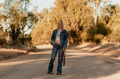 barrel racer in australia wearing feared and fearless unchained eight tee tshirt shirt with mavericks western straw hat next to stock horse. Australian cowgirl is wearing barrel racing buckle  country allure bag ariat crusiers ladies